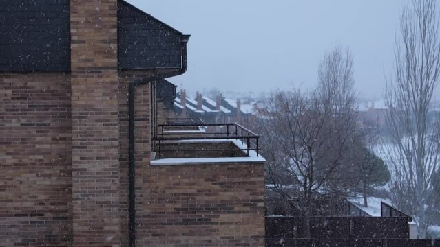 Cinematic shot of snow falling in a residential area, gloomy weather atmosphere.