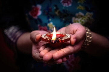 Happy Diwali. Woman's hands holding lit candle(Diya). Diwali celebration