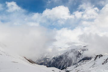 Fototapeta na wymiar Snowy rocky mountains merging with the clouds.