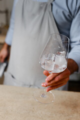 Bartender prepares cocktail with ice. Hand with glass close-up
