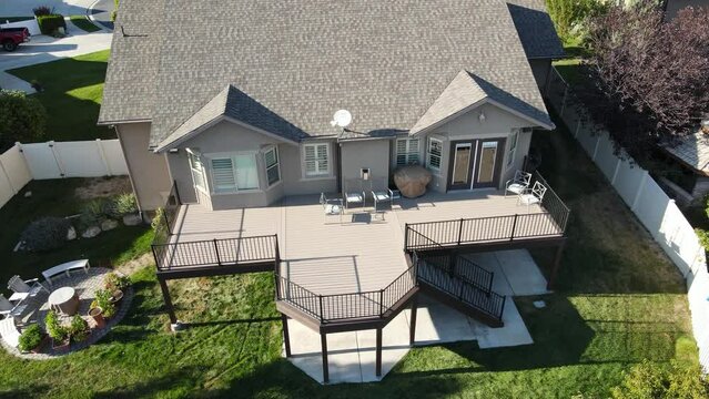 Newly constructed elevated patio deck on a home's backyard - tilt down ascending aerial view