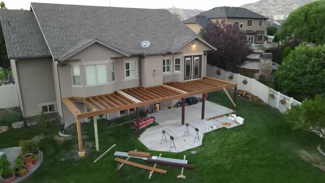 Framework of an elevated backyard patio deck during construction - pull back ascending aerial