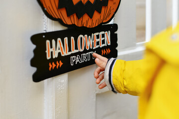 A kid with Carved pumpkin hanging on the fence of the house