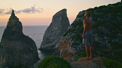 Naklejka premium Zen man relaxing sunset at beautiful ocean cliff edge. Focused yogi breathing
