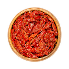 Sun dried tomatoes, in a wooden bowl, isolated from above. Red ripe plum tomatoes, cut into...