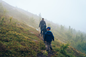 Hiker with children on footpath  in the fog. Norway