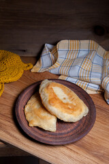 Clay plate of fried meat pies on wooden table.