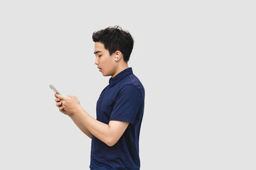 Asian businessman wearing wireless earphone is texting on  smart phone.