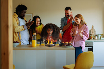 Girl blows out birthday candles at home.