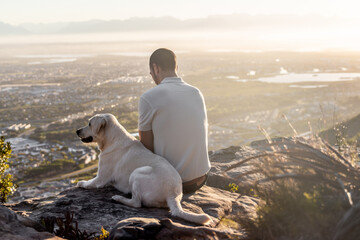 Man and dog on a hill overlooking a town - Powered by Adobe