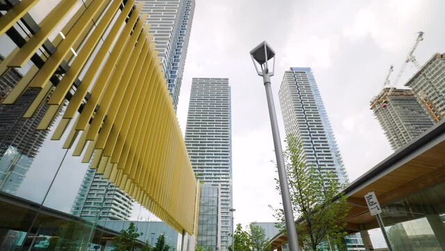 Looking up and walking towards tall high rise condominium residence buildings at the VCM Vaughan Metropolitan Centre.