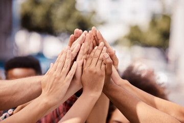 Hands, teamwork and solidarity with a group of people standing outdoor in the city in a huddle or...