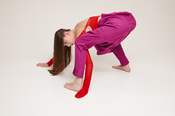 Portrait of young beautiful girl wearing shirt instead pants, tights on hands isolated over grey background. Crawling