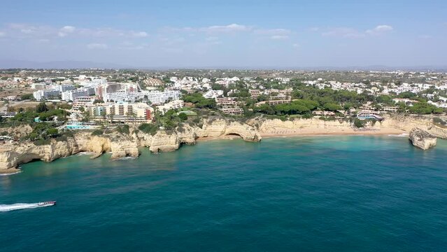 Carvoeiro city, perspective from above. Situated in Lagoa, Algarve, South of Portugal, is a travel destination. Typically, Portuguese landscape. Boat passing in first plan. Drone following the boat.