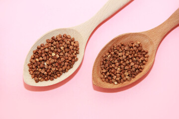 small grains of brown natural buckwheat in a wooden spoon