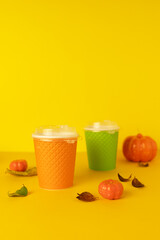 autumn pumpkin latte on orange background in colorful paper cup. coffee to go in the fall. copy space, text, vertical