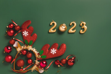 Festive layout numbers 2023, accessories New Year, wreath of horns, toys tinsel green background