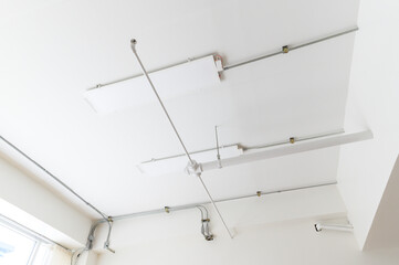 Electrical wires and pipes on house concrete ceiling background, plastic hoses with cables in empty room. Lines of pvc tubes, conduit after professional work. Renovation of home or factory interior