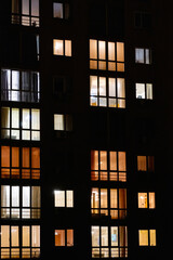 Illuminated windows of night multistory apartment building. Lighted night windows of house. City life background.