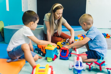 'boys, look, what a cool car I have' - teacher enjoying with her kids at kindergarten. High quality photo