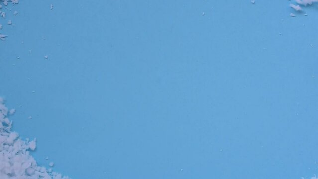 white polystyrene beads wind blown blue background with space for text
