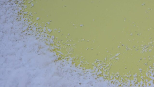 white polystyrene beads wind blowing yellow background with space for text