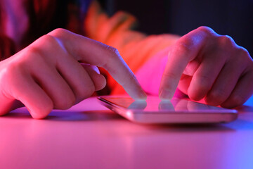 Use of mobile phone in trendy neon lights. Creative vivid color of ultraviolet red and blue. Hands...