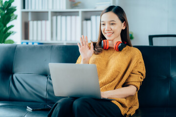 Beautiful young asian woman with headphones relaxing on the sofa. She is listening to music using smartphone . Chill out and leisure concept