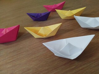 Some colorful paper boats on a black background 