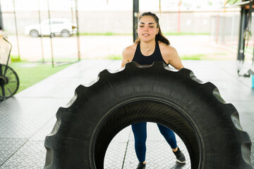 Fototapeta na wymiar Athletic woman doing tire flip exercises at the gym