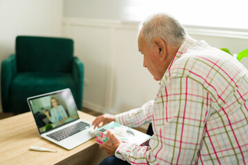 Rear view of an ill old man talking with a virtual doctor