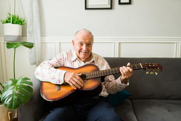 Happy senior old man smiling loving music playing the guitar