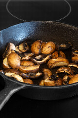 Frying chestnut mushrooms in a cast iron frying pan, on an electric hob stove