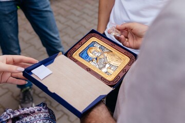 a woman and a man holds an Orthodox icon of the guardian angel