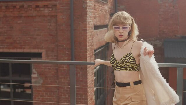 Stylish Caucasian girl in vintage sheep fur coat and animal printed bra dancing vogue outdoors in sunlight