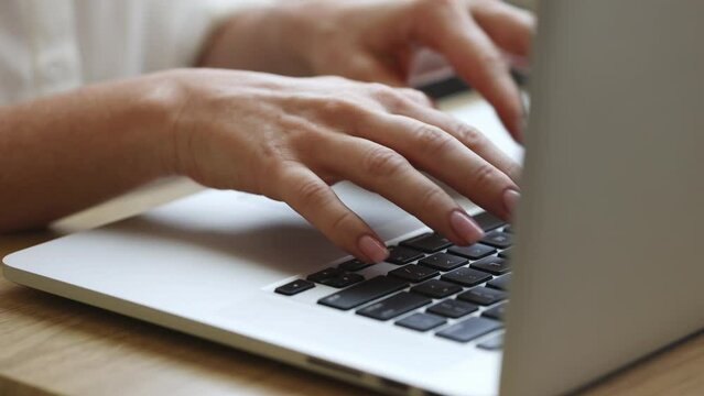 Freelancer working on a laptop from home, female hands in frame