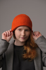young girl model in orange cap and grey coat isolated on grey background. Product photo mockup for fashion brands and marketplaces.