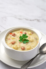 Close-up of a bowl of potato soup with vegetables and pieces of meat. Vertical shot from a high angle and copy space.