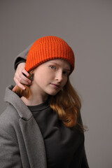 young girl model in orange cap and grey coat isolated on grey background. Product photo mockup for fashion brands and marketplaces.