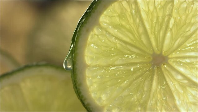Drop of Lime Juice flow down the surface of a ripe juicy Lime slice. Slow Motion 4K