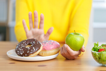 Young woman refuse junk food while choose to eat healthy fresh fruit for her healthy