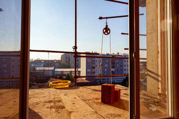 Work in progress on terrace with bricks, building under construction with scaffolding, tube for...
