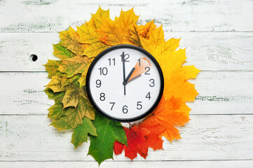 Fall time change still life with maple tree foliage and wall clock