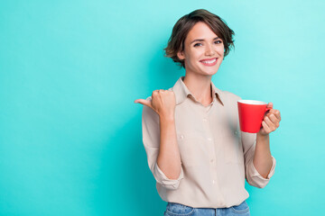 Photo of cheerful adorable lady office worker arm direct empty space nice proposition enjoy hot tasty tea isolated on cyan color background