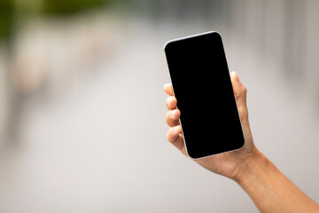 Fototapeta na wymiar Hand holding modern smartphone with black empty screen, mockup