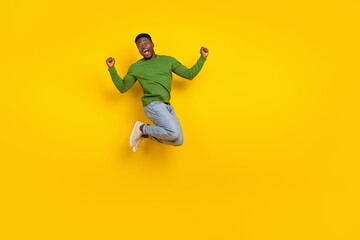 Fototapeta na wymiar Full length body size view of attractive ecstatic guy jumping having fun attainment isolated over shine yellow color background