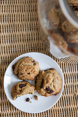 cookies in a jar and cookies on a plate.
a bite taken out of one cookie