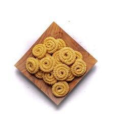 Crunchy fried homemade Chakli,chakkuli, murukku in a wooden traditional plate on white background top view