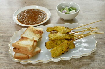 grilled pork satay couple bread dipping with sweet peanut sauce and pickled vegetable  Indonesian food on plate