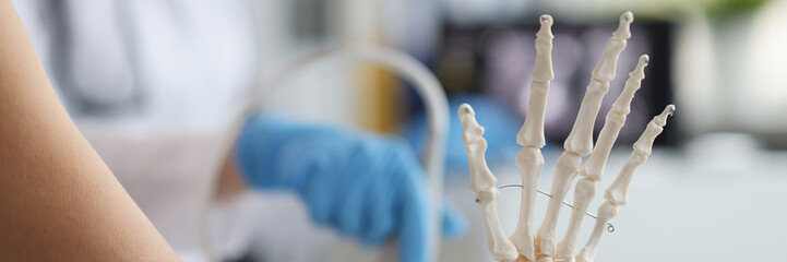 On the doctor's table is a plastic skeleton of fingers, blurry